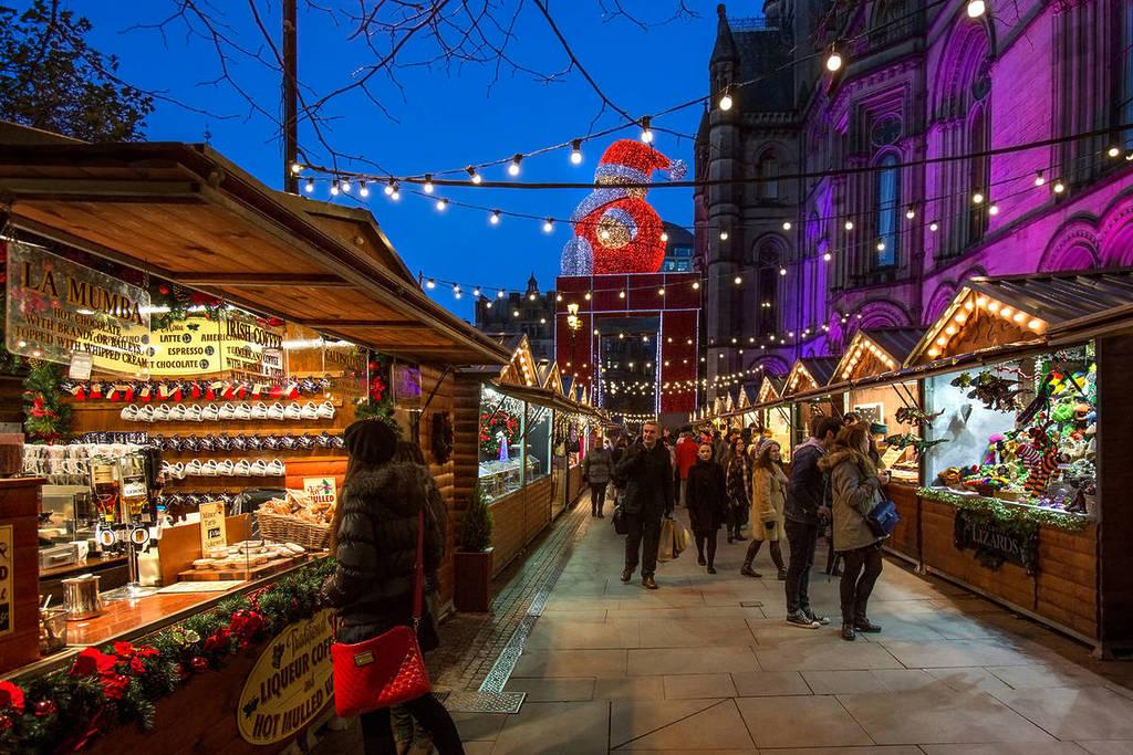 people walking through the manchester christmas markets in the early evening